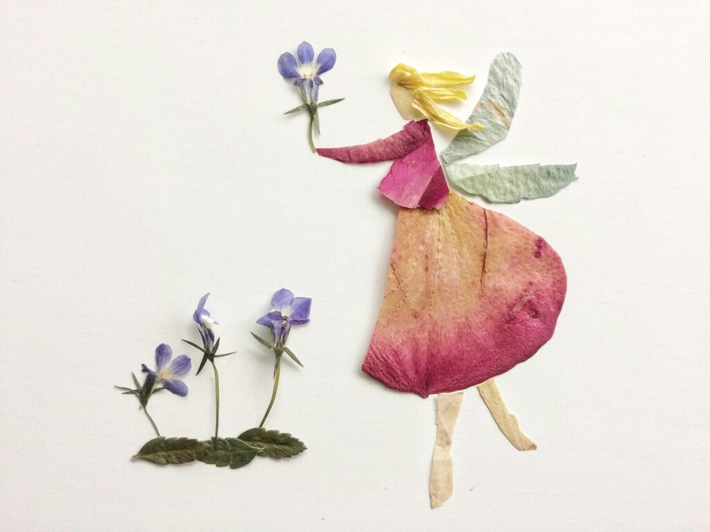 A whimsical fairy made of pressed flowers and leaves, set on a white background.